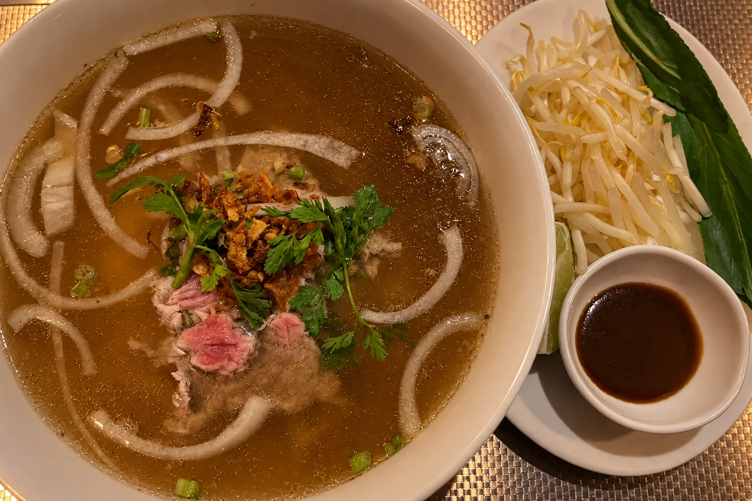 P4. Raw beef pho in a white bowl, side plate, dim lighting